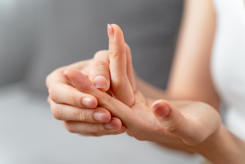 Closeup young woman sitting on sofa holds her wrist. hand injury, feeling pain. Health care and medical concept